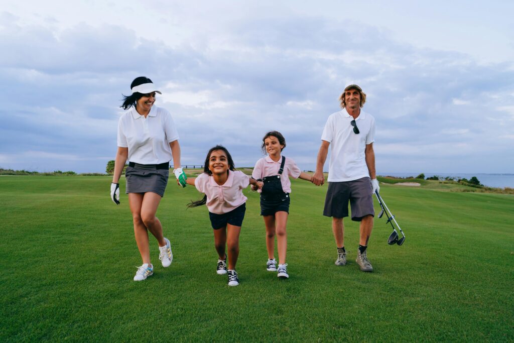 A happy family walking together on a lush golf course, enjoying a sunny day.